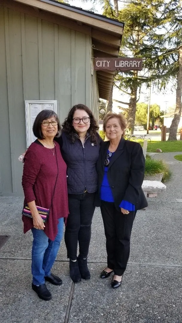Three women standing next to each other in front of a building.