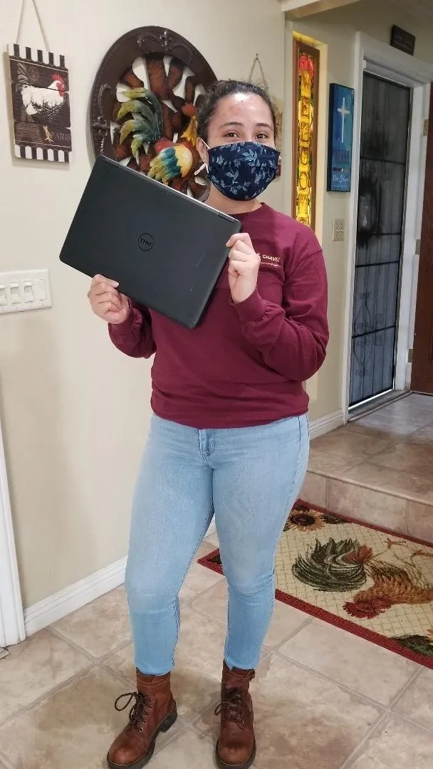 A woman holding up an open laptop computer.