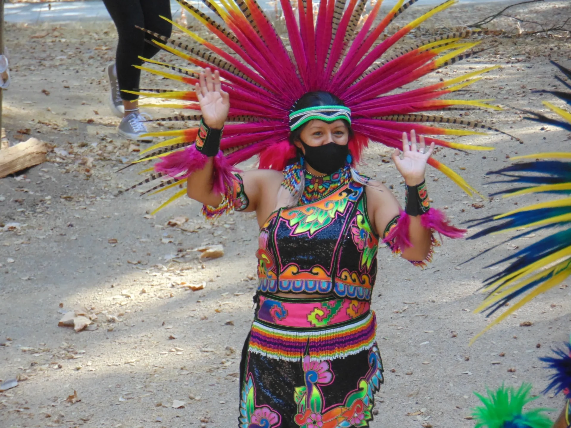 A person in colorful costume and headdress on the beach.