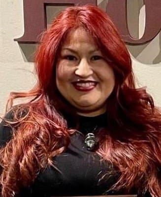 Anietra website photo A woman with red hair and black shirt smiling.